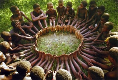 Foto de crianas de uma tribo africana sentadas com os pés juntos, formando um círculo